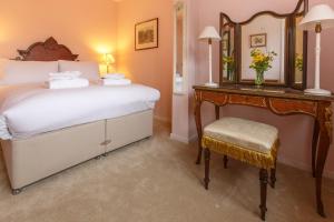 a bedroom with a bed and a mirror and a chair at Jasmine Cottage in Kelsale