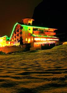 ein Gebäude mit Neonbeleuchtung am Strand in der Nacht in der Unterkunft Alps Oriental Wellness HOTEL in Campodolcino