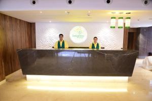 Dois homens de coletes amarelos atrás de uma mesa grande. em Lemon Tree Hotel Siliguri em Siliguri