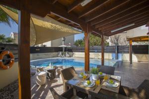 un patio con tavolo e sedie accanto alla piscina di Ayia Napa Tropical Beach Villa a Ayia Napa