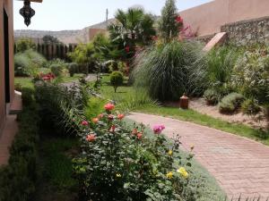 a garden with flowers and plants on a brick path at Riad Asmaa Agadir in Agadir