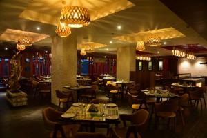 シリグリにあるLemon Tree Hotel Siliguriのテーブルと椅子、シャンデリアのあるレストラン