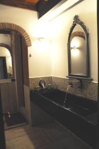 La salle de bains est pourvue d'un lavabo noir et de deux miroirs. dans l'établissement La Corte di Nonno, à Frascati