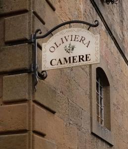 una señal en el lateral de un edificio de ladrillo en Oliviera Camere, en Pienza