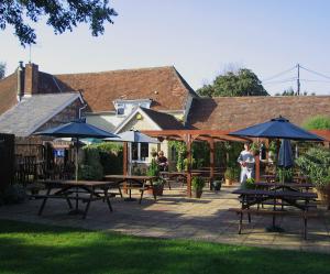 un gruppo di tavoli e ombrelloni su un patio di The Pelican Inn a Stapleford