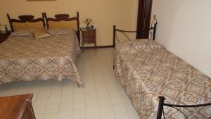 a bedroom with two beds and a tiled floor at La Casetta sul Corso in Gubbio