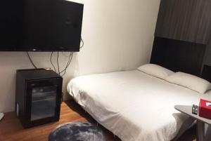 Dormitorio pequeño con cama y TV en Gathering, en Kaohsiung