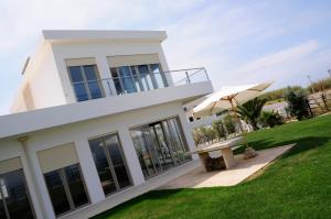 a white house with a bench and an umbrella at Silver Coast Vacation - Your Unique Inn in Lourinhã