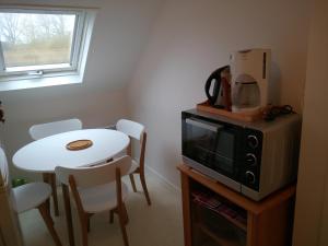 a small kitchen with a table and a microwave at Le Jardin Fleuri in Ploemel
