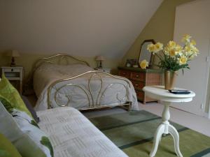 a bedroom with a bed and a table with a vase of flowers at Le Jardin Fleuri in Ploemel +18 photos
