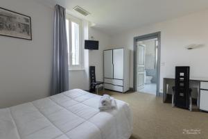 a bedroom with a white bed and a bathroom at Hôtel Pedussaut in Saint-Gaudens