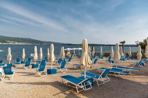 a bunch of chairs and umbrellas on a beach at Apartments Nice View in Krk