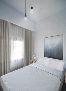 een slaapkamer met een wit bed en een raam bij Imeres Studios & Apartments in Polykhrono
