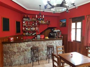un bar en un restaurante con paredes y mesas rojas en La Casa Vieja en Valdeón, en Soto de Valdeón