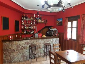 a bar in a restaurant with red walls and tables at La Casa Vieja en Valdeón in Soto de Valdeón