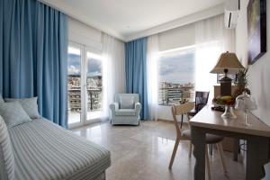 Schlafzimmer mit einem Bett und einem Schreibtisch mit einem Tisch und Stühlen in der Unterkunft Panorama Junior Suites in Kavala