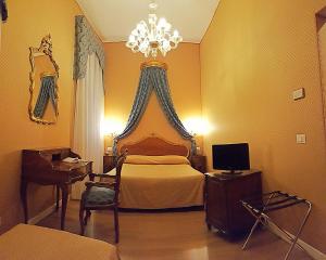 1 dormitorio con 1 cama con lámpara de araña y escritorio en Hotel Locanda Canal, en Venecia