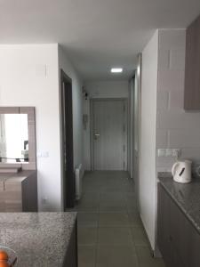 a white kitchen with a hallway leading to a door at First line Apartment in Alicante