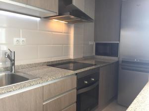 a small kitchen with a sink and a stove at First line Apartment in Alicante