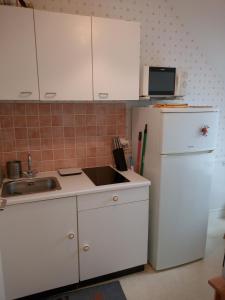 a white kitchen with a sink and a refrigerator at Le Jardin Fleuri in Ploemel