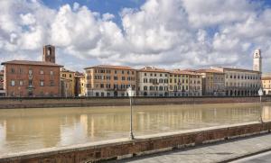 a group of buildings next to a river at the river in Pisa