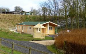 un petit bâtiment jaune avec un toit vert sur une colline dans l'établissement Dollys Hideaway Cabin, à Goulsby