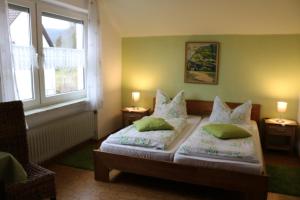 ein Schlafzimmer mit einem Bett mit zwei Kissen und zwei Fenstern in der Unterkunft Pension Hermes in Wallenborn