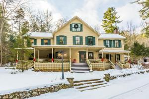 Una gran casa amarilla con nieve en el suelo en Snow Goose Bed and Breakfast, en Keene Valley