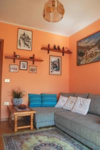 een woonkamer met een grijze bank en oranje muren bij Rustico Massimo - Rebomaholidays in Tignale