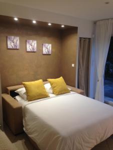 a bedroom with a large white bed with yellow pillows at Charmant Studio à Uchaud in Uchaud