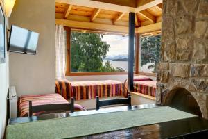 sala de estar con chimenea de piedra, mesa y sillas en Bungalows La Caleta D.T. 026/17 en San Carlos de Bariloche