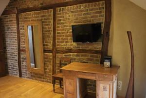 um quarto com uma parede de tijolos, uma televisão e uma mesa de madeira em Les houx de Mathieu em Engis