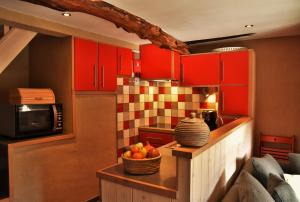 a kitchen with red cabinets and a bowl of fruit on a table at Les houx de Mathieu in Engis