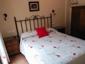 Una cama con una almohada roja encima. en Apartamentos Valle del Guadalquivir, en Arroyo Frío