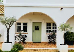 a white house with a green door and tables at Quinta da Lua in Tavira
