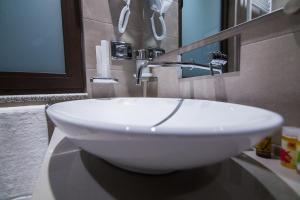 lavabo blanco en el baño con espejo en Hotel Regal, en Korçë