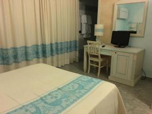 a bedroom with a bed and a desk with a television at Hotel Monreale in Sardara