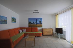 a living room with an orange couch and a television at Ferienwohnungen Matzner in Admont