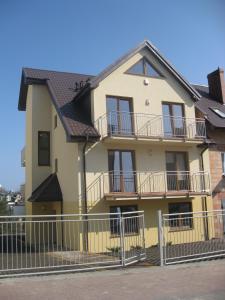 żółty dom z balkonem i ogrodzeniem w obiekcie Willa Tomaszek we Władysławowie