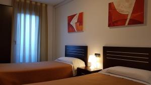 Una habitación de hotel con dos camas y una ventana. en Apartamentos Puerta Muralla, en Teruel