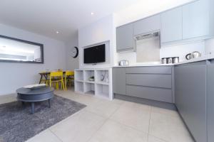 a kitchen with white cabinets and a tv in it at Sandbanks Road in Poole