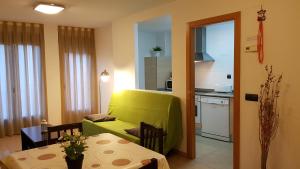 Una sala de estar con un sofá verde y una cocina. en Apartamentos Puerta Muralla, en Teruel