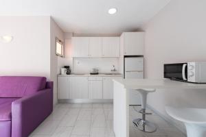 a kitchen with white cabinets and a purple couch at eó Las Gacelas in Playa del Ingles