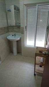 baño con lavabo y ventana con persianas en Hostal Tamarindos en Matalascañas