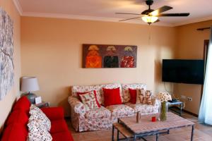 a living room with a red couch and a tv at Villa Carmen in Caleta De Fuste