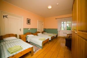 three beds in a room with wooden floors at Sagadi Manor Hostel in Sagadi