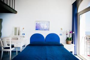 a blue bed in a bedroom with a desk and a window at Hotel Villa Iulia in Ventotene