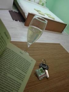 a glass of wine and a book and keys on a table at Apartman Andjela 1 in Vrdnik