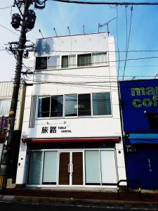 a white building on the side of a street at Fukuoka Tabiji Hostel & Guesthouse in Fukuoka