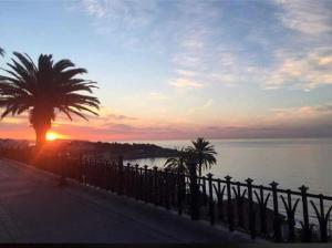 a sunset over the water with a fence and a palm tree at Cala Azul 304-306 Tamarit in Tamarit